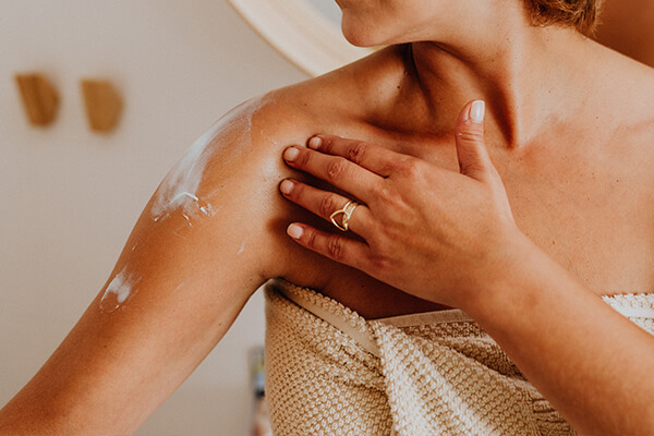 woman applying lotion on shoulder